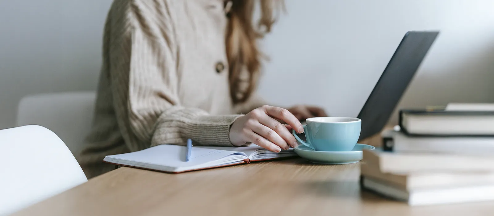 Woman working on her laptop while holding a cup of coffee, represents how you can find rates & insurance options that fit your needs.
