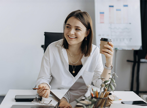 Woman in a business meeting holding a coffee cup, represents how you can find support to heal from trauma and achieve your goals.