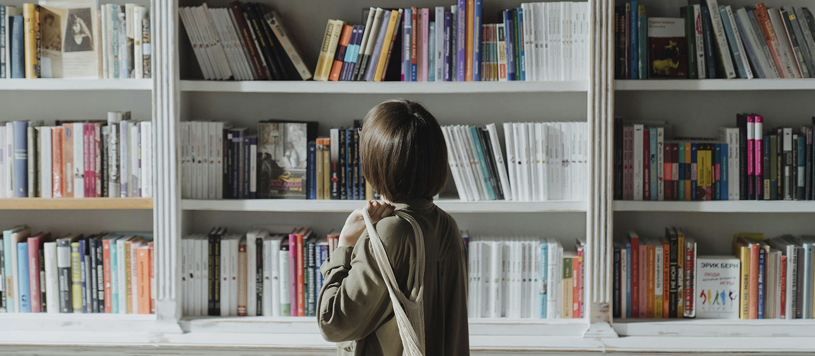 Woman looking at a book shelf, represents how you can find mental health articles and blog posts by Susan Podbielski.