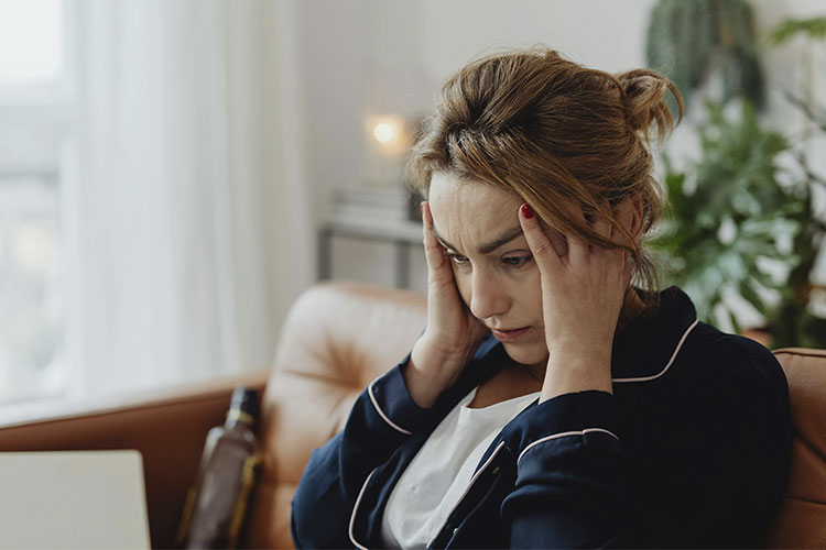 Woman with her hands on her head, looking overburdened, represents the cost of always being the capable one and not setting boundaries.