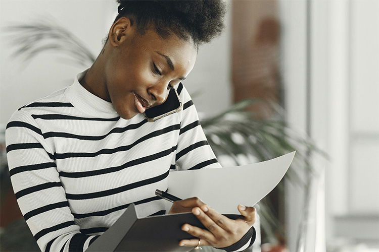 Busy woman on the phone while writing things down, represents how productivity can be a trap for high achieving woman dealing with depression.