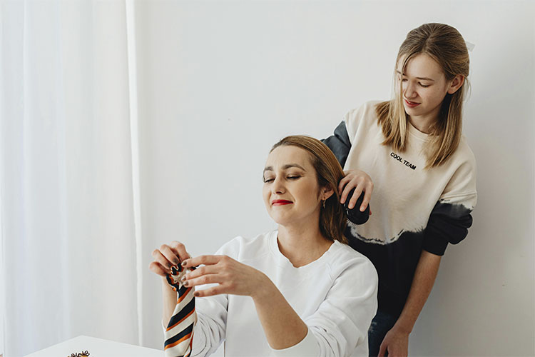 Teen daughter brushing her mother's hair, represents the eldest daughter syndrome and the toll of growing up too fast.