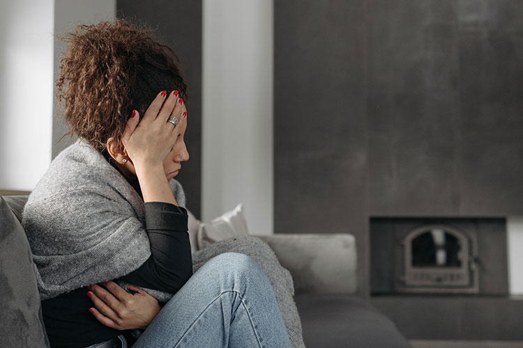 Woman curled up on the couch looking distressed, represents the hormonal mood disorders across a woman's life.
